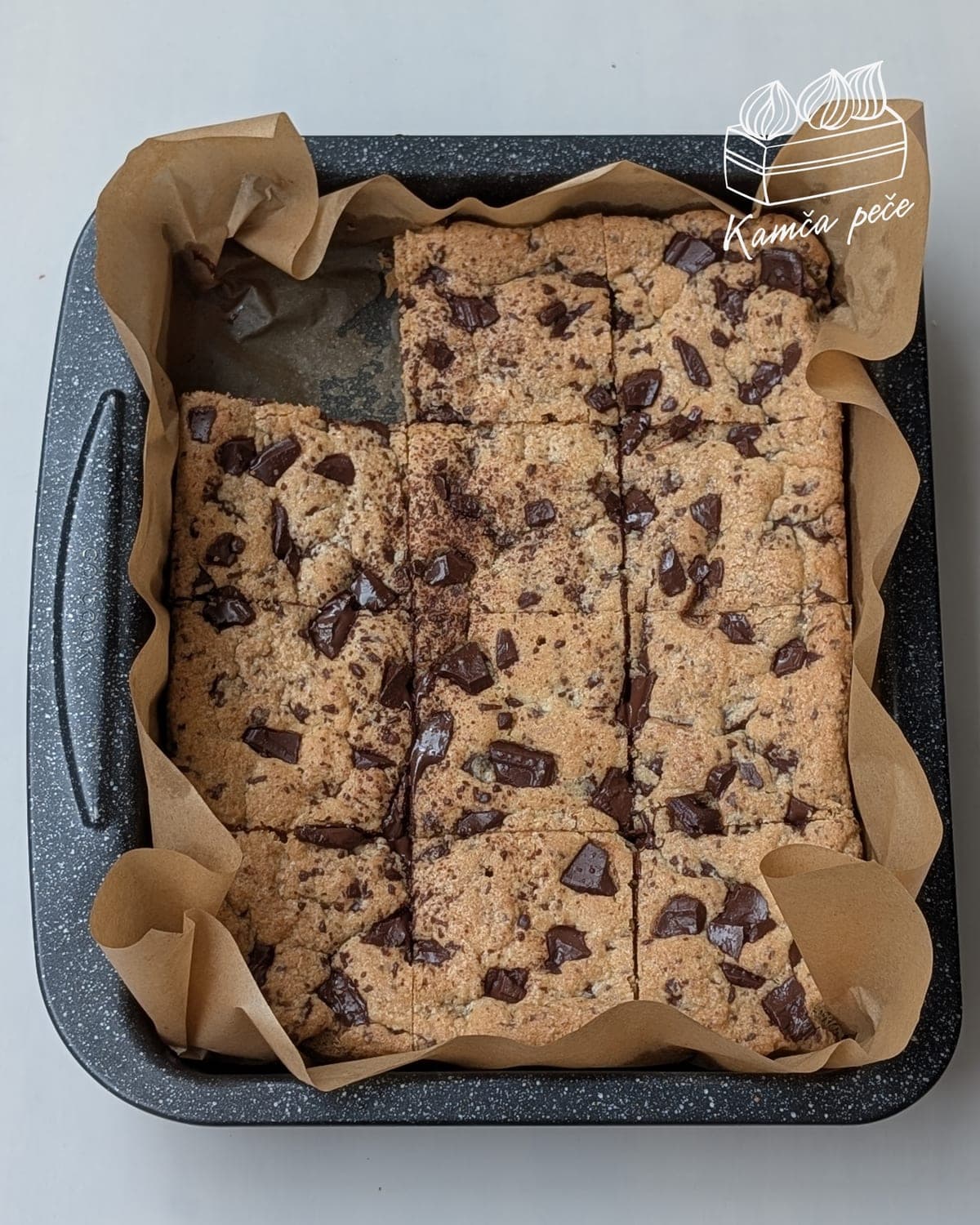 Nakrájené cookie bars s kousky čokolády v plechu s pečicím papírem
